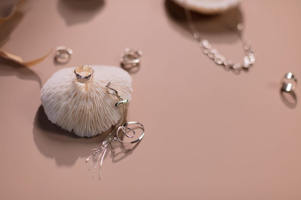 Sterling silver rings and a chain necklace arranged on a soft pink surface