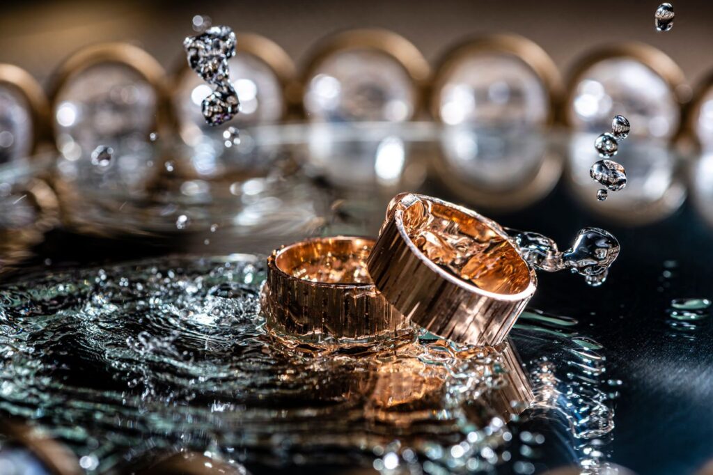Two gold rings on a wet reflective surface