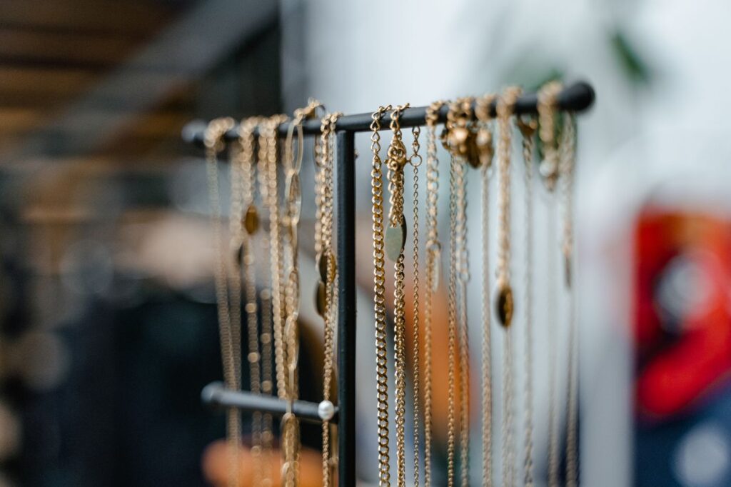 Gold chain necklaces hanging from a black metal jewelry stand