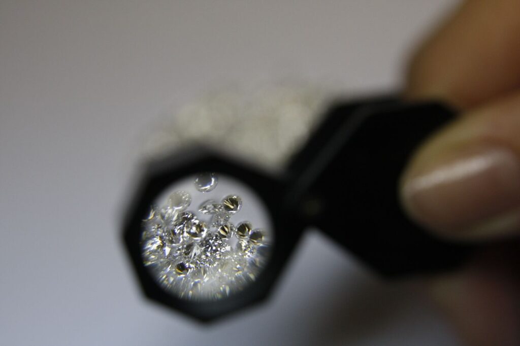 Loose diamonds seen through a jeweler's loupe held between two fingers