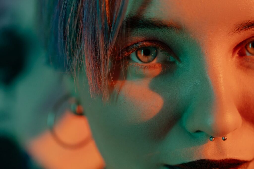 Close-up of a woman with a septum piercing in warm and teal light