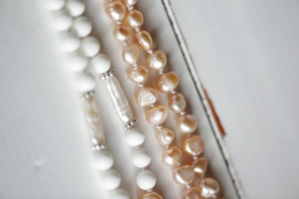 Strands of white and peach pearl necklaces laid side by side
